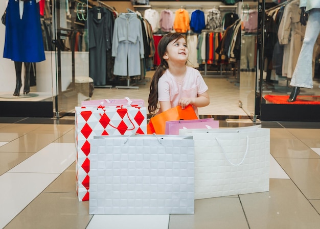 A little girl is shopping in colorful paper bags child in a clothing store