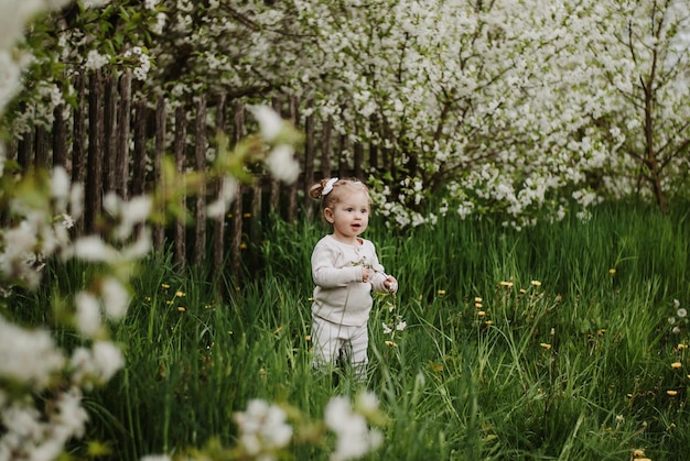 a little girl is standing on the grass. a child in a blooming garden . a girl with a smile.