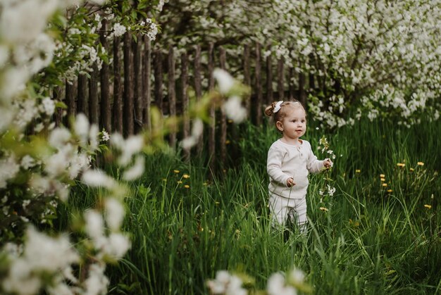 a little girl is standing on the grass. a child in a blooming garden . a girl with a smile.