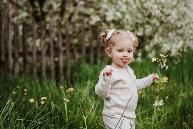 a little girl is standing on the grass. a child in a blooming garden . a girl with a smile.