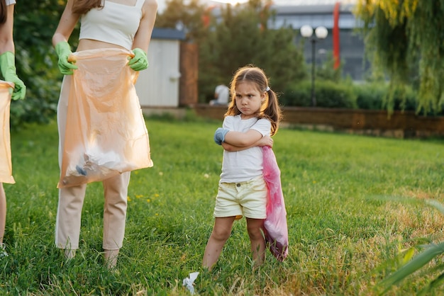 A little girl is upset about cleaning garbage in the park during sunset Environmental care recycling