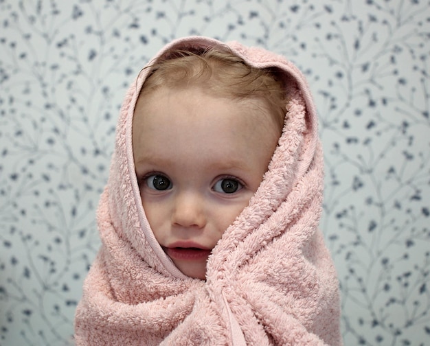 A little girl is wrapped in a towel after bathing Closeup portrait