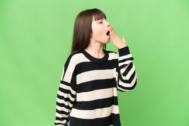 Little girl over isolated green chroma key background yawning and covering wide open mouth with hand