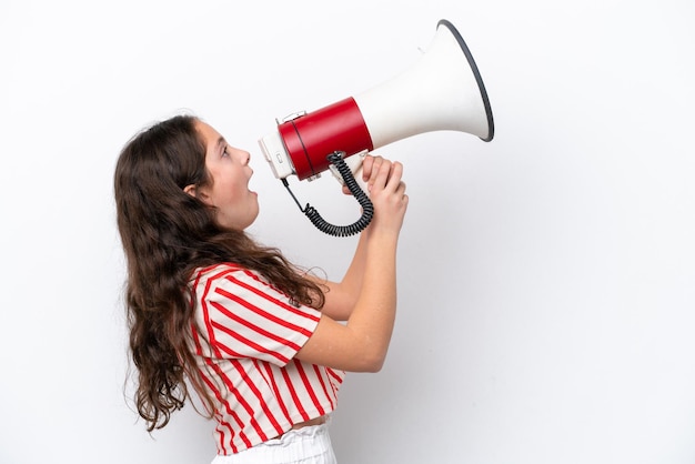 Little girl isolated on white background shouting through a megaphone to announce something in lateral position