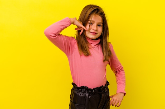 Little girl isolated on yellow wall showing a mobile phone call gesture with fingers