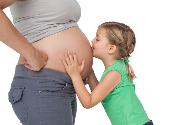 Little girl kissing her mothers baby bump