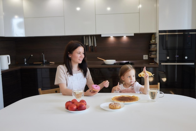 Little girl in the kitchen eats pancakes