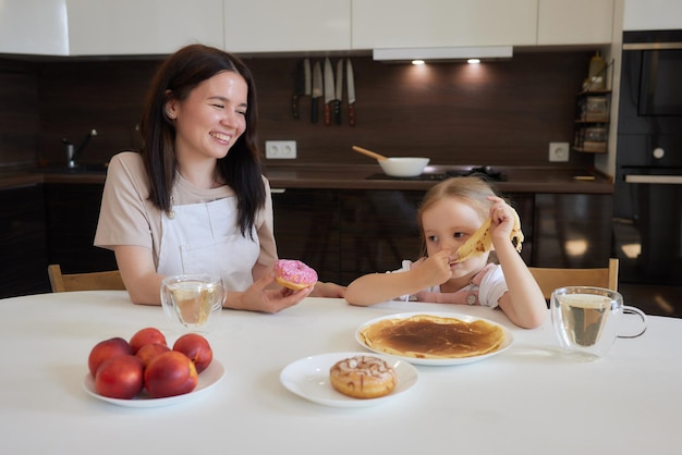 Little girl in the kitchen eats pancakes