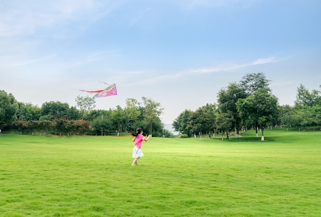 The little girl kites the kite on the lawn