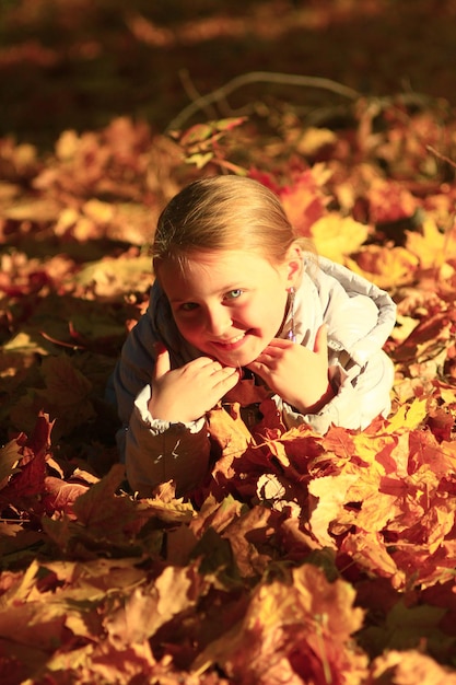 little girl laying in yellow leaves in the autumn park