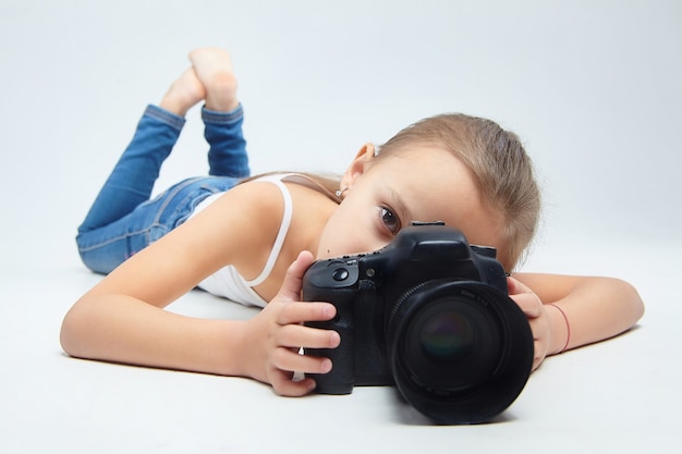 A little girl lies in the Studio with a camera.