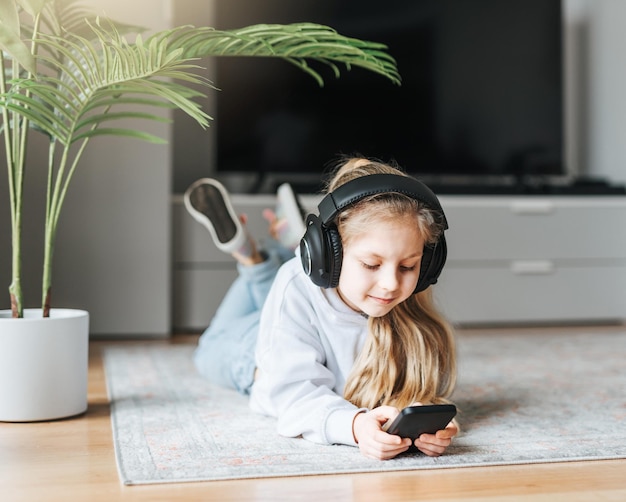 Little girl listening music lying on the floor