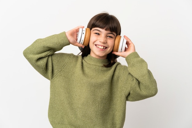 Little girl listening music with a mobile isolated on white wall listening music