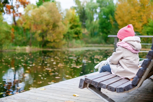 Little girl looking at the pond in the autumn park