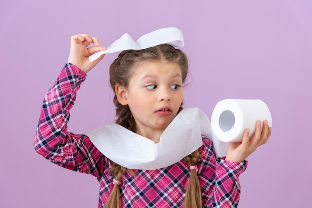 The little girl looks at the toilet paper and is surprised