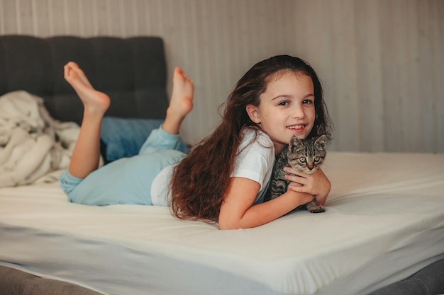 little girl lying in bed and hug the kitten