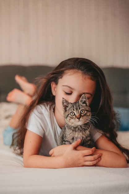 little girl lying in bed and hug the kitten