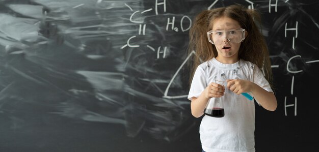 Little girl makes experiments in chemistry lesson explosion during the experiment  place for text co...