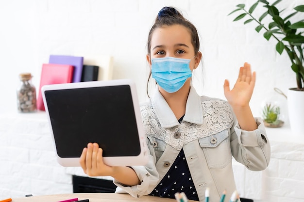 little girl in medical mask studying at home. epidemic, pandemic.