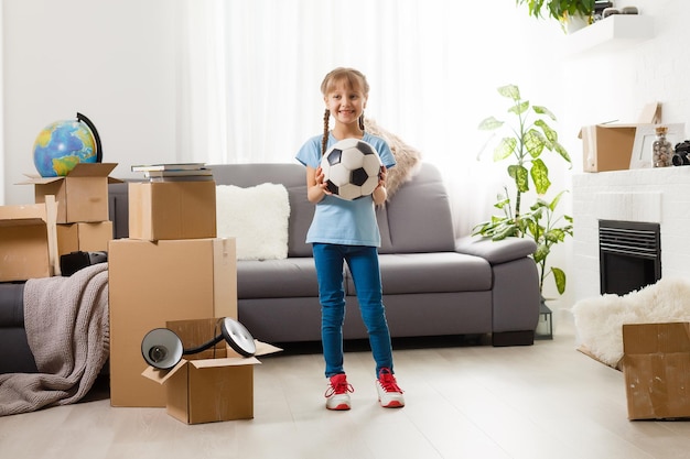 Little girl moving into new house, near cardboard box.