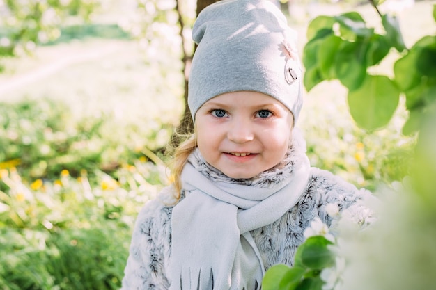 A little girl in nature admires the white flowering of spring trees