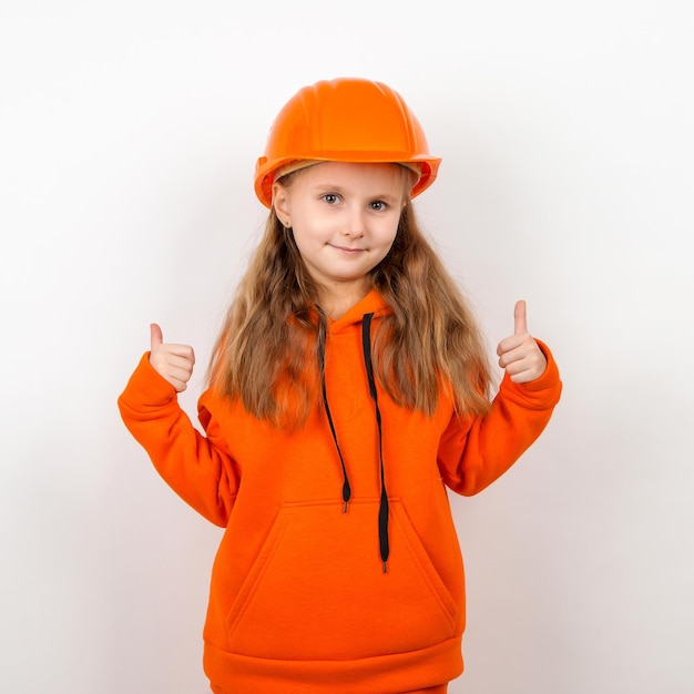 A little girl in an orange suit and a construction helmet a concept of young builder Portrait white background Labor Day