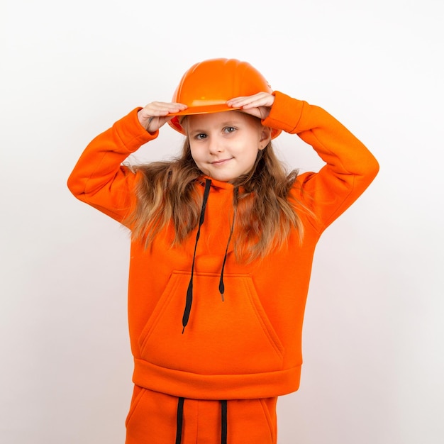 A little girl in an orange suit and a construction helmet a concept of young builder Portrait white background Labor Day