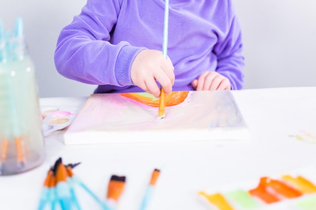 Little girl painting on canvas with arcylic paint.