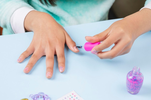 Little girl painting her nails at home with clear varnish