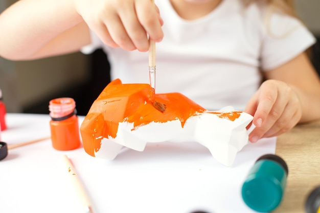 A little girl paints a toy fox made of clay DIY concept