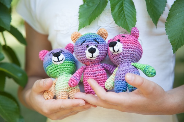 Little girl in the park holding a knitted toy. Handmade, amigurumi