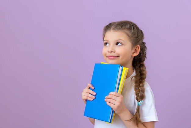 A little girl in pigtails and a book in her hands on purple background