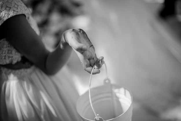 a little girl in a pink dress is holding a white bucket for flowers. black and white photo