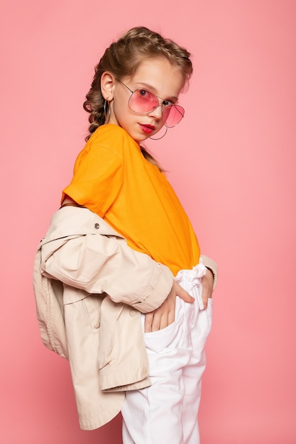 Little girl in pink glasses. Trendy fashion style stylish funtime concept. Vertical full-size full-length portrait of laughing cute sweet adorable lovely charming girl isolated pink wall