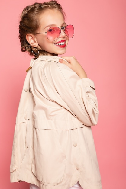 Little girl in pink glasses. Trendy fashion style stylish funtime concept. Vertical full-size full-length portrait of laughing cute sweet adorable lovely charming girl isolated pink wall