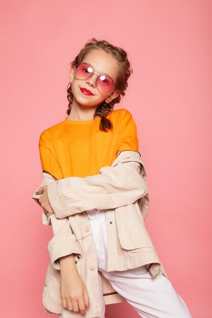 Little girl in pink glasses Trendy fashion style stylish funtime concept Vertical fullsize fulllength portrait of laughing cute sweet adorable lovely charming girl isolated pink background