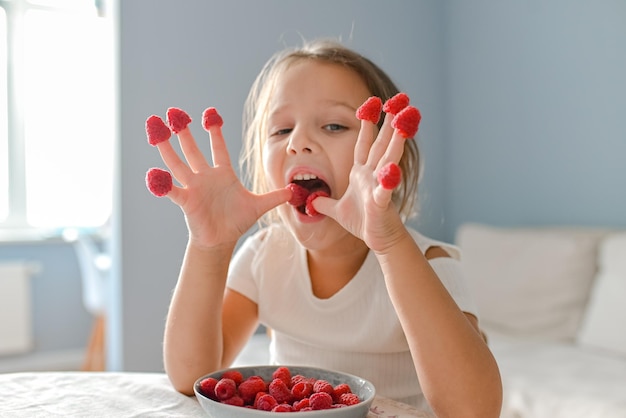 The little girl played with raspberries on her fingers