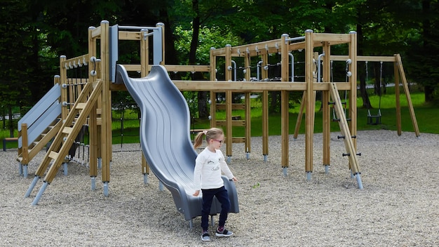 Little girl on a playground Child playing outdoors in summer Kids play on school yard Happy kid in kindergarten or preschool Children having fun at daycare play ground Toddler on a slide