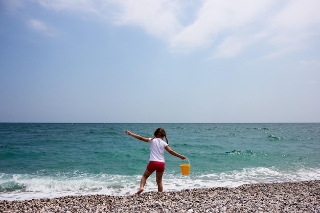 Little girl playing on the beach near by blue sea