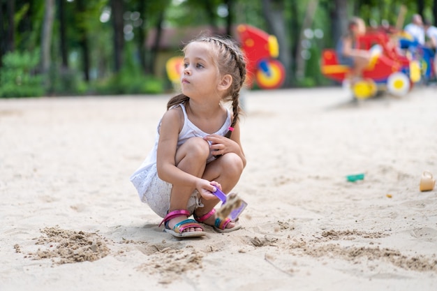 Little Girl Playing Sandbox Playground Digging Sand Shovel Building Sand Figure Summer Day. Caucasian Female Child 5 years Have Fun Outdoor