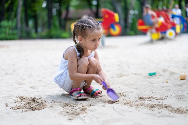 Little Girl Playing Sandbox Playground Digging Sand Shovel Building Sand Figure Summer Day Caucasian Female Child 5 years Have Fun Outdoor