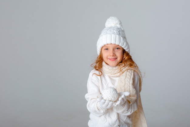 Little girl playing snowball in a hat on a white background