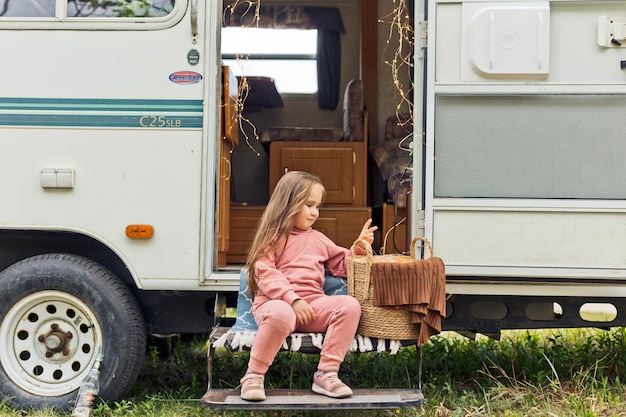 Little girl playing on the steps of a travel trailer