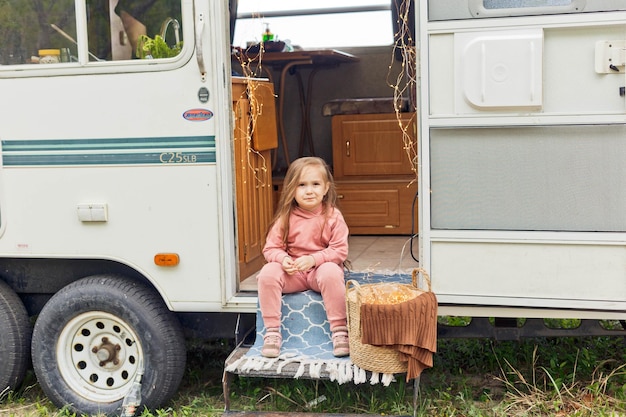 Little girl playing on the steps of a travel trailer