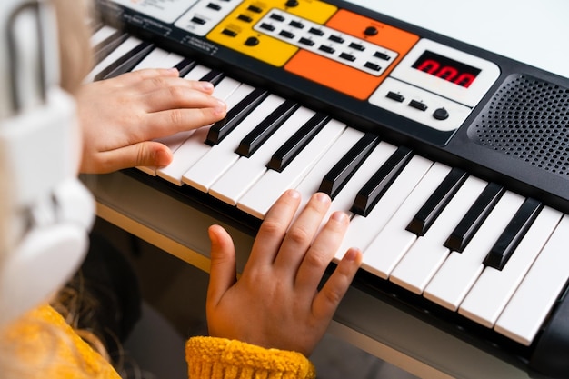 A little girl playing the synthesizer the concept of teaching children music hands closeup