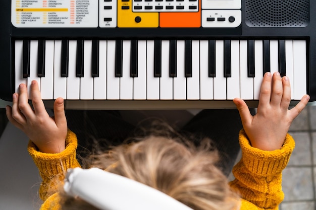 A little girl playing the synthesizer the concept of teaching children music top view