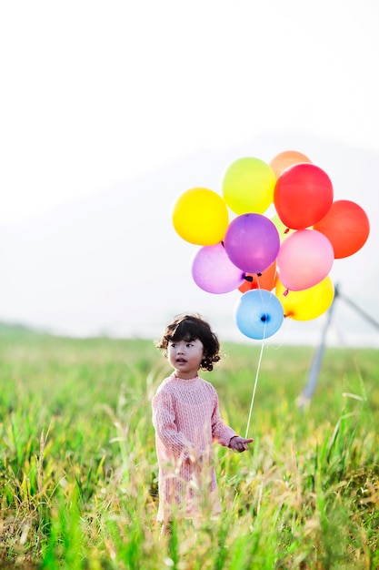 Little girl playing with balloons on wheat field