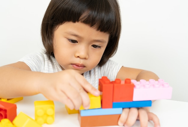 Little girl playing with colorful toy blocks on white,Kids play with educational toys