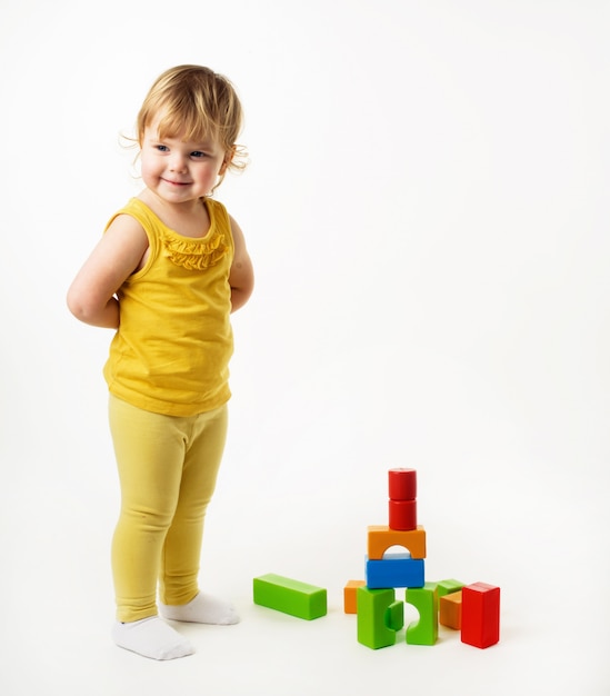 Little girl playing with colorful toy blocks