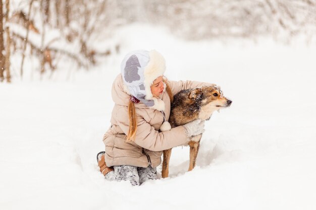 Little girl playing with a dog in the winter forest. winter fun